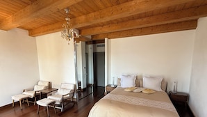 A spacious bedroom with a large bed, a wooden ceiling, and a chandelier. - Entre Ciel et Mer Hotel (Bonifacio)