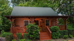 Eine rustikale Holzhütte mit Veranda, Holzstufen und einem Metalldach.
