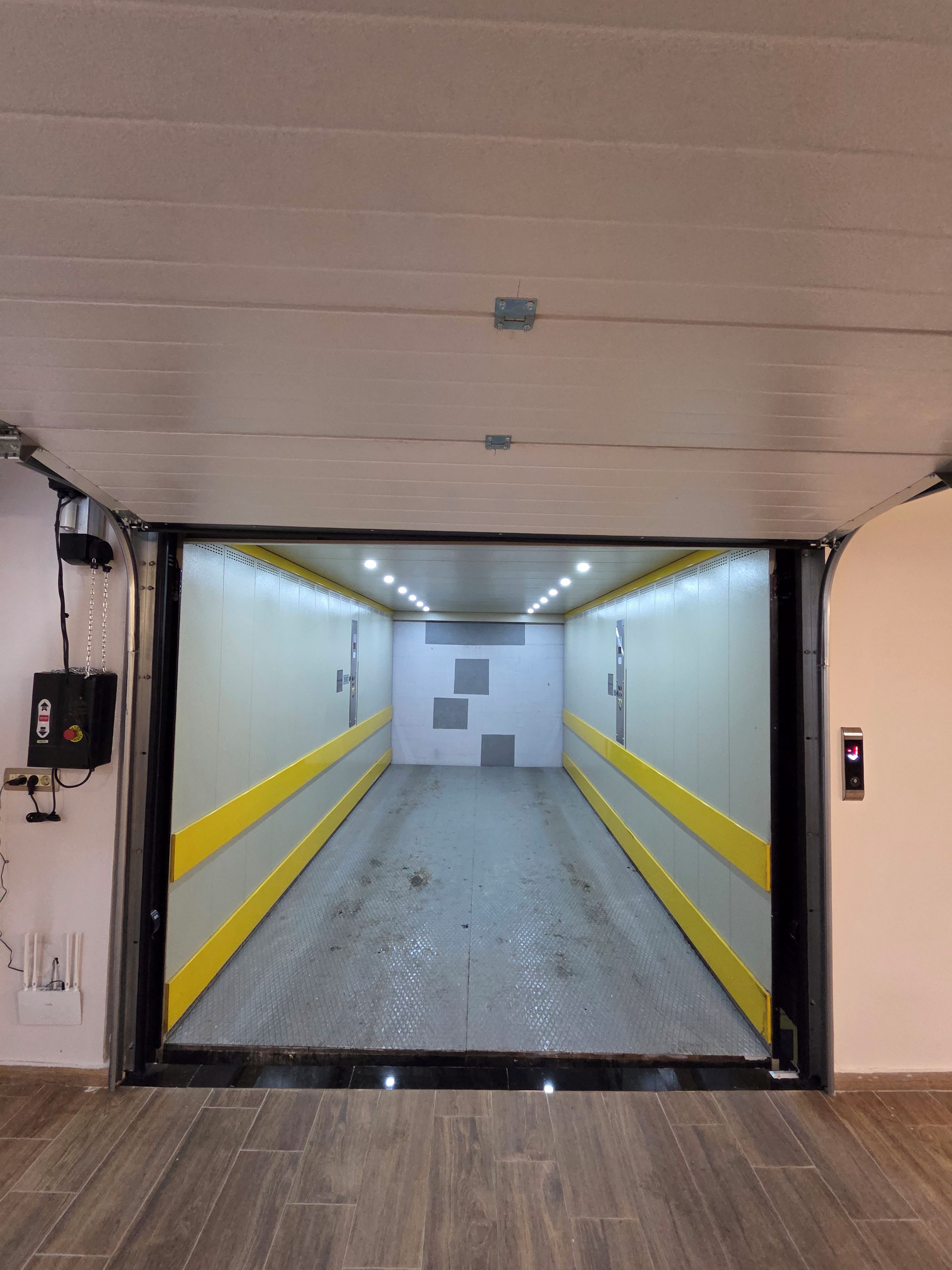 An elevator shaft with a control panel on the right and a power outlet on the left.