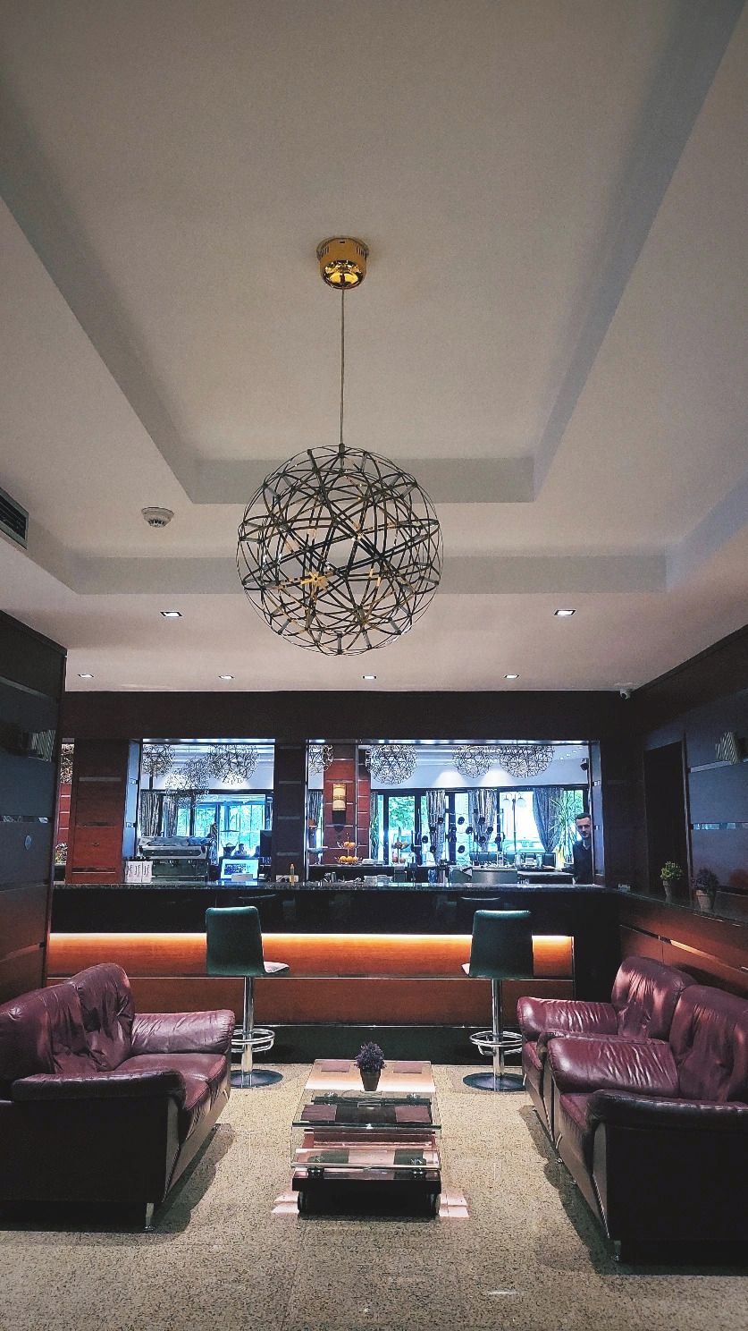 A modern lobby with a bar area, leather seating, and a unique spherical light fixture.