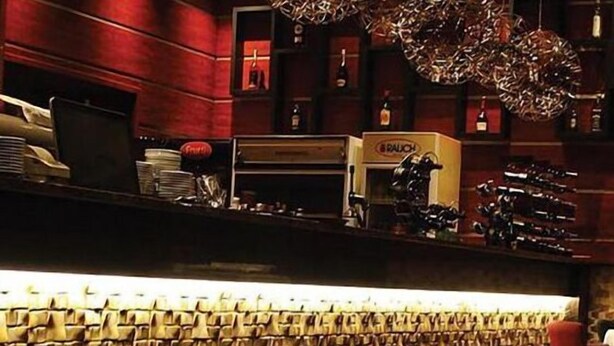 Un espace bar avec un comptoir, des étagères remplies de bouteilles et un mur décoratif.