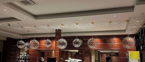 Un interior moderno con mostrador de recepción, zona de estar e iluminación decorativa.