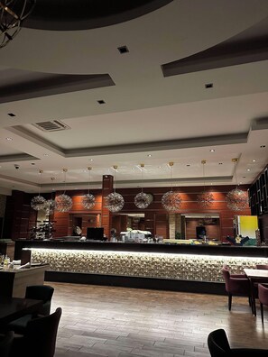 A modern interior with a reception desk, seating area, and decorative lighting. - Hotel Royal (Pristina)