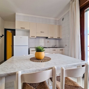Una cucina moderna con mobili bianchi, un piano di lavoro in marmo e una pianta in vaso.