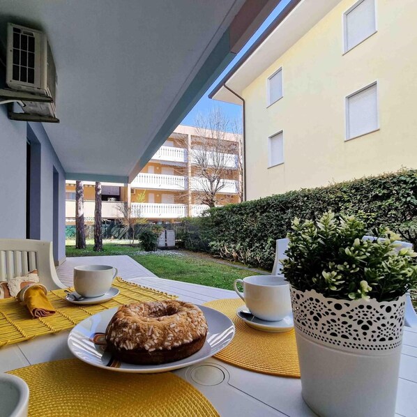 A balcony with a table set for two, a donut, and a potted plant.
