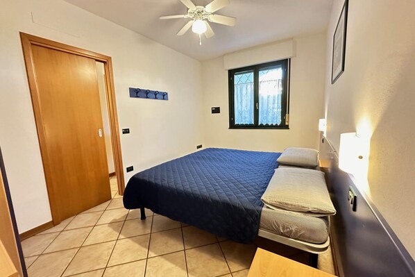 A bedroom with a bed, a window, a ceiling fan, and a door. - Relaxing Getaway With Pool and Garden in Bibione (San Michele al Tagliamento)