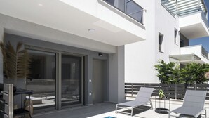 Ein modernes Gebäude mit Pool auf dem Dach, Glasgeländern und Außenbereich zum Sitzen.