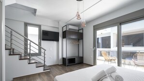 Ein modernes Schlafzimmer mit Bett, Fernseher, Kleiderschrank und einem Balkon mit Sitzgelegenheiten.