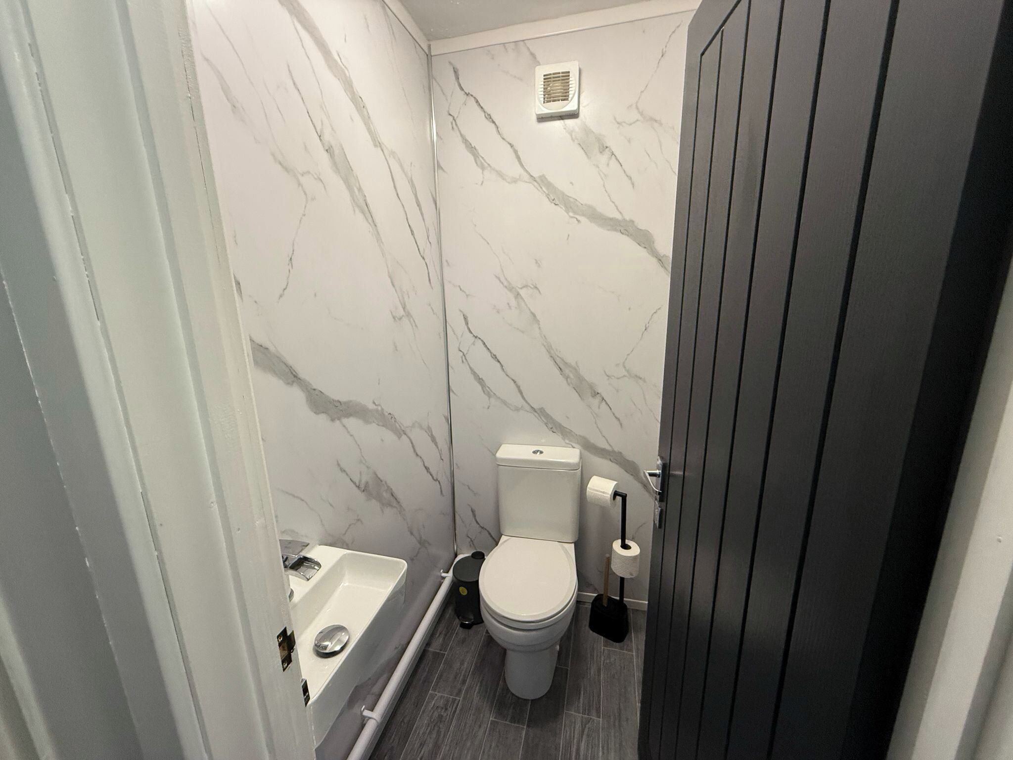 A compact bathroom with a toilet, sink, and shower.