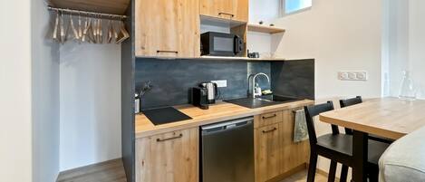 A compact kitchen with wooden cabinets, a dishwasher, a microwave, and a sink.