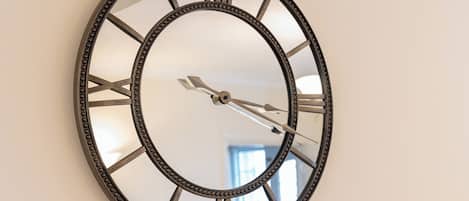 A wall-mounted clock with Roman numerals and a decorative frame.