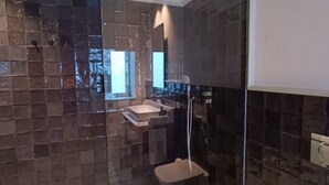 A modern bathroom with a glass shower enclosure, a sink, and a toilet.