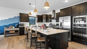 A modern kitchen with dark cabinets, stainless steel appliances, and a wooden island with bar stools.