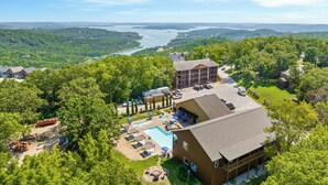 A lodge with a pool, outdoor seating, and a view of a lake and mountains.