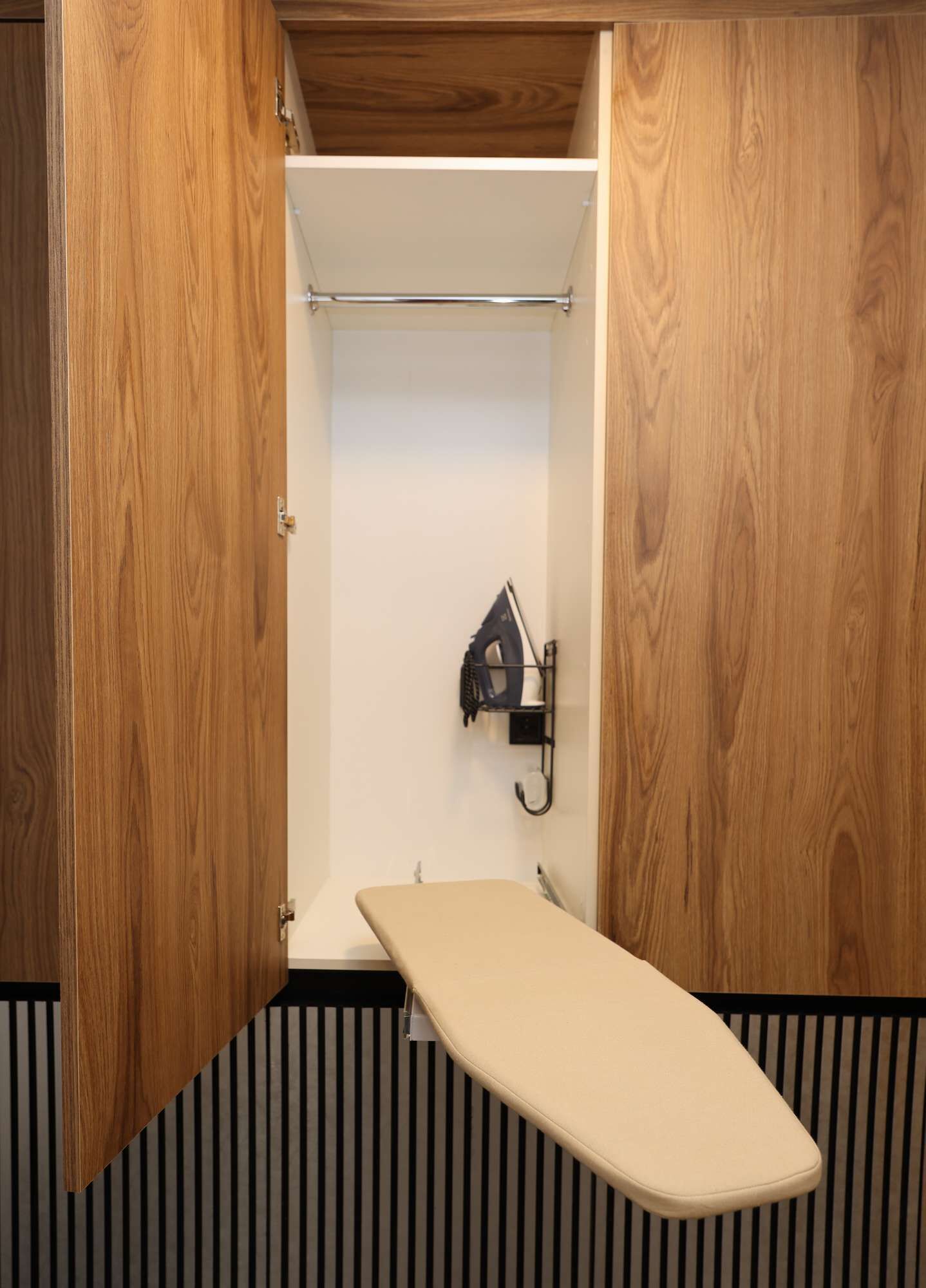 Une petite pièce fermée, avec une porte en bois, un mur blanc et un sol à rayures noires et blanches.