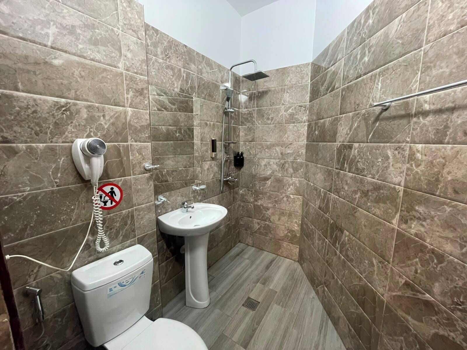 A bathroom with a toilet, sink, and shower.