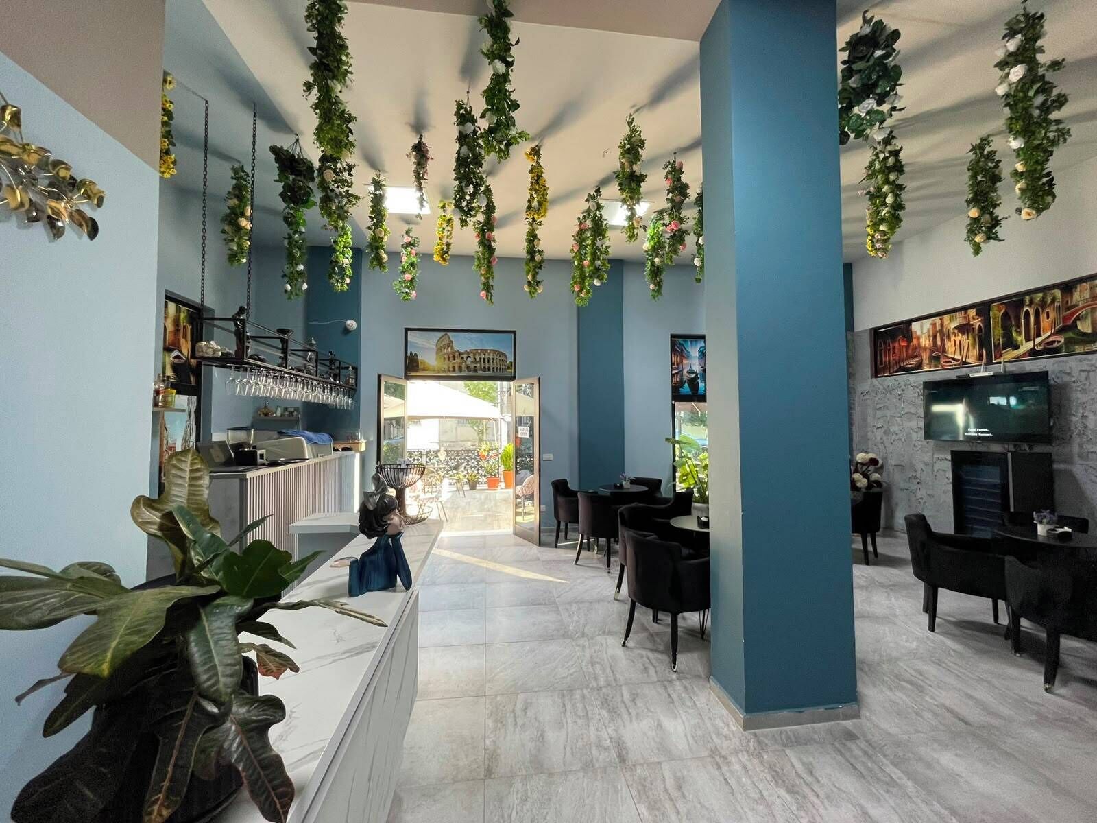Un interior moderno con una zona de bar, asientos y plantas colgantes.