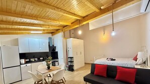Un apartamento compacto con kitchenette, comedor y un dormitorio con cama y sofá.