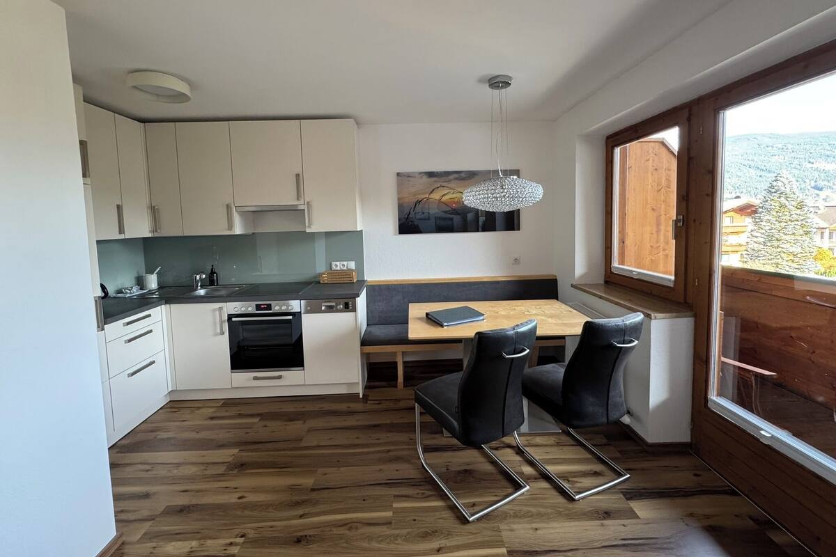 A modern kitchen with white cabinets, a wooden dining table, and black chairs.