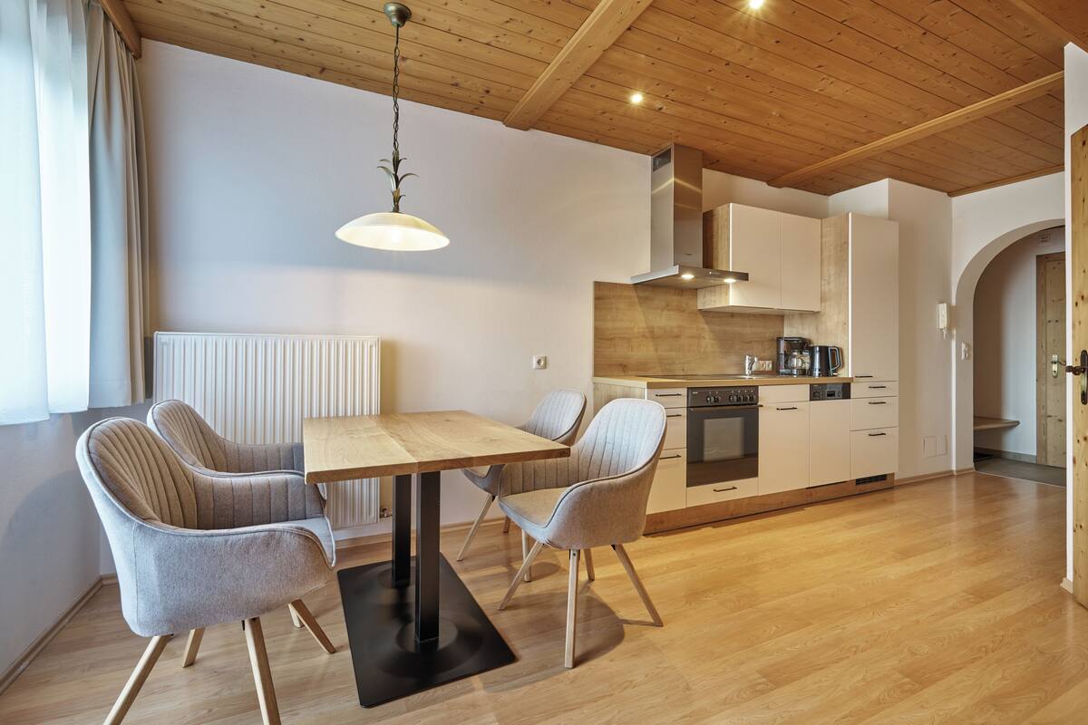 A modern kitchen with wooden cabinets, a central island, and a dining area with a table and chairs.