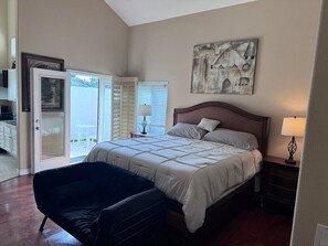 A bedroom with a large bed, a chair, a nightstand, and a painting on the wall.