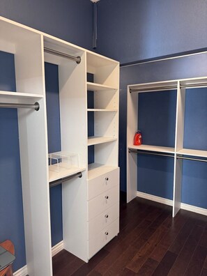 A walk-in closet with open shelving, drawers, and a hanging rod.