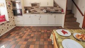 A compact kitchen with white cabinets, a tiled backsplash, and a small dining area with a table set for two.