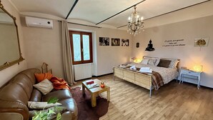 A cozy living room with a sofa, a coffee table, a bed, and a chandelier.