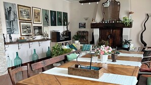 A dining area with a wooden table and chairs, surrounded by shelves with books and decorative items.