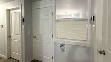 A hallway with white doors, a notice sign, and a window with blinds.