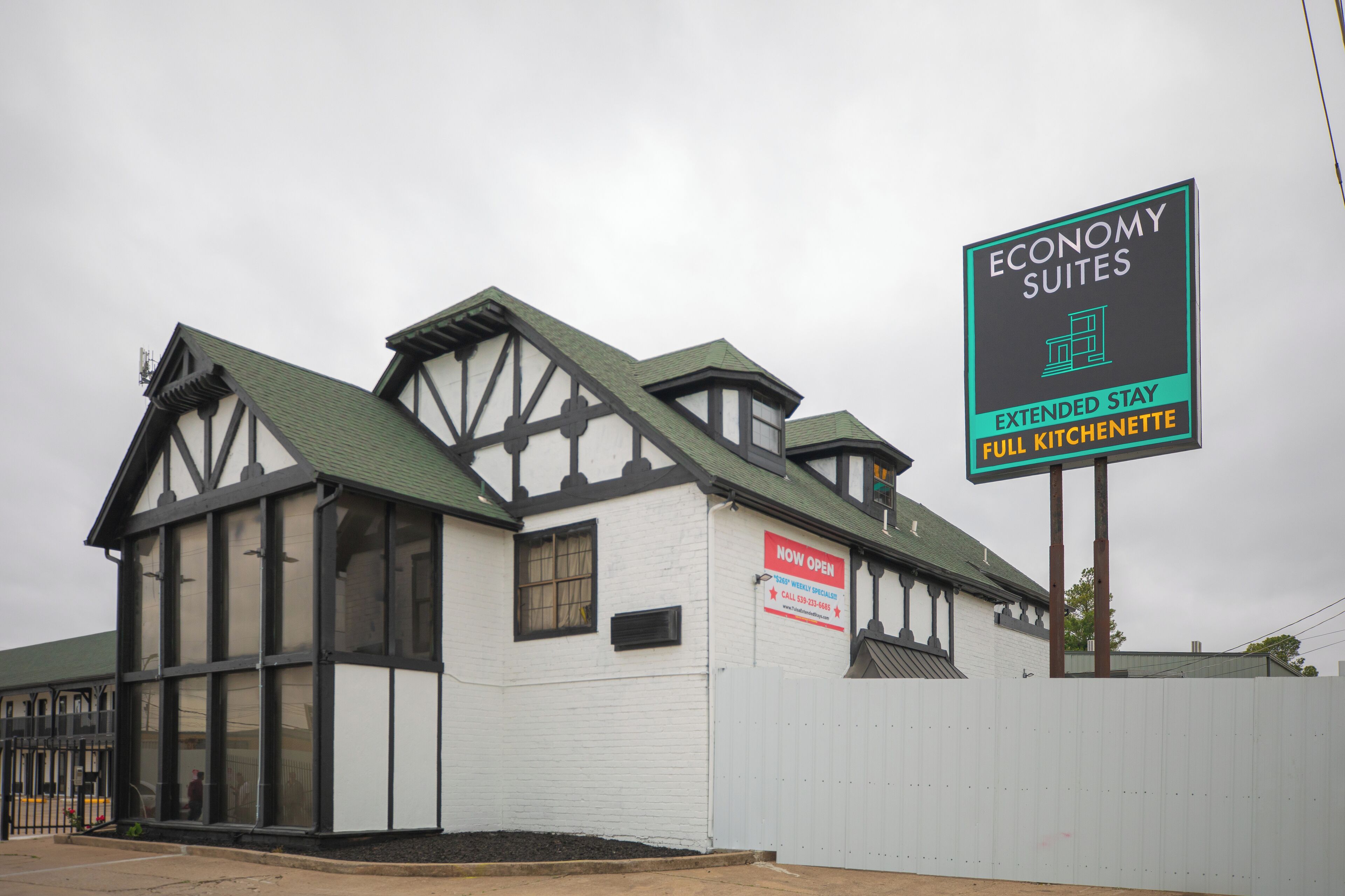 Un edificio con un cartel que anuncia Suites Económicas, Estancia Prolongada y Cocineta Completa.
