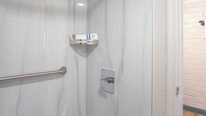 Moderni kylpyhuone, jossa on suihku, marmoriseinät ja puulattia.
