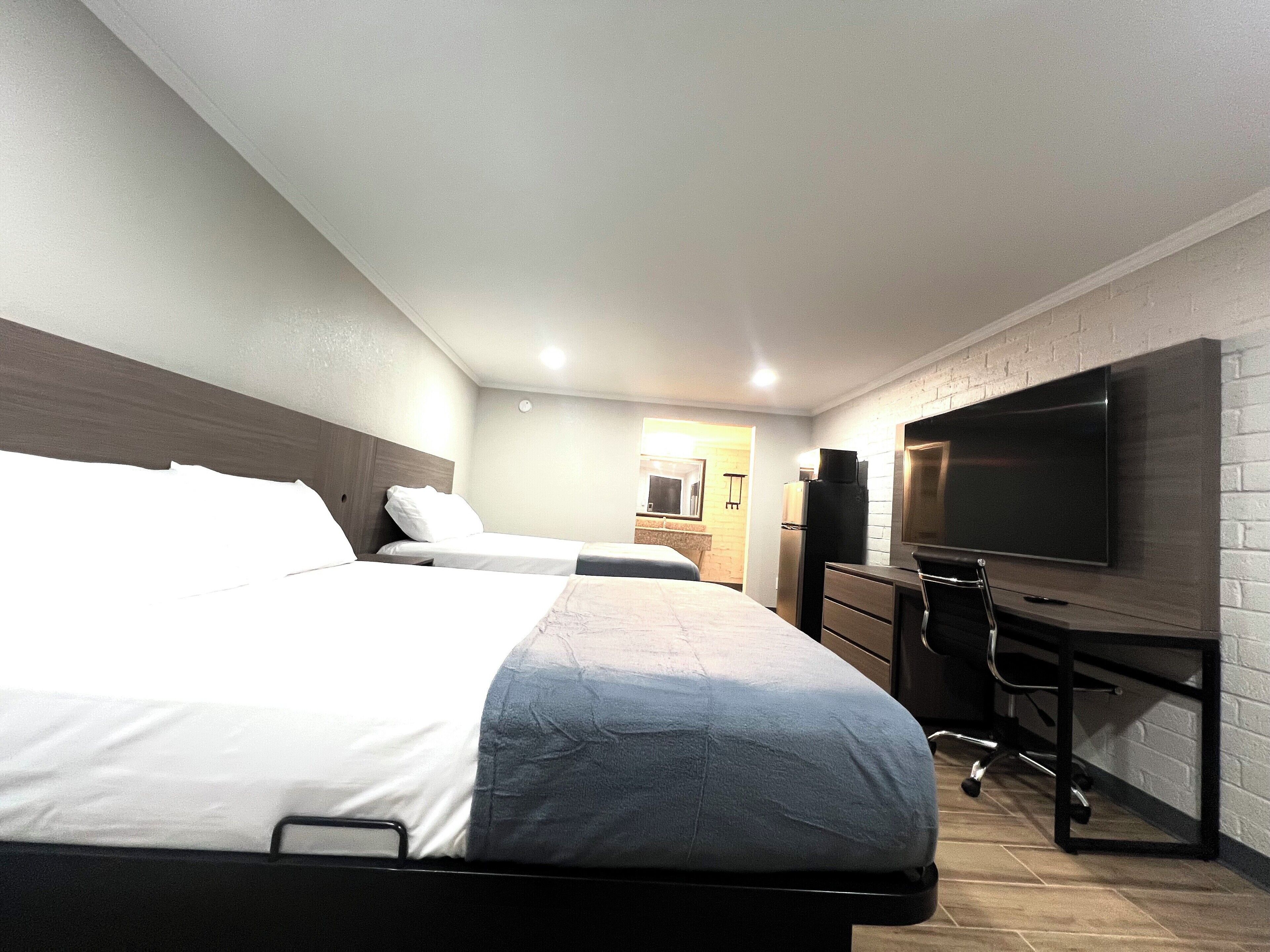 Une chambre d’hôtel avec deux lits, une télévision, un bureau et une armoire.