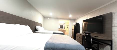 A hotel room with two beds, a TV, a desk, and a wardrobe.