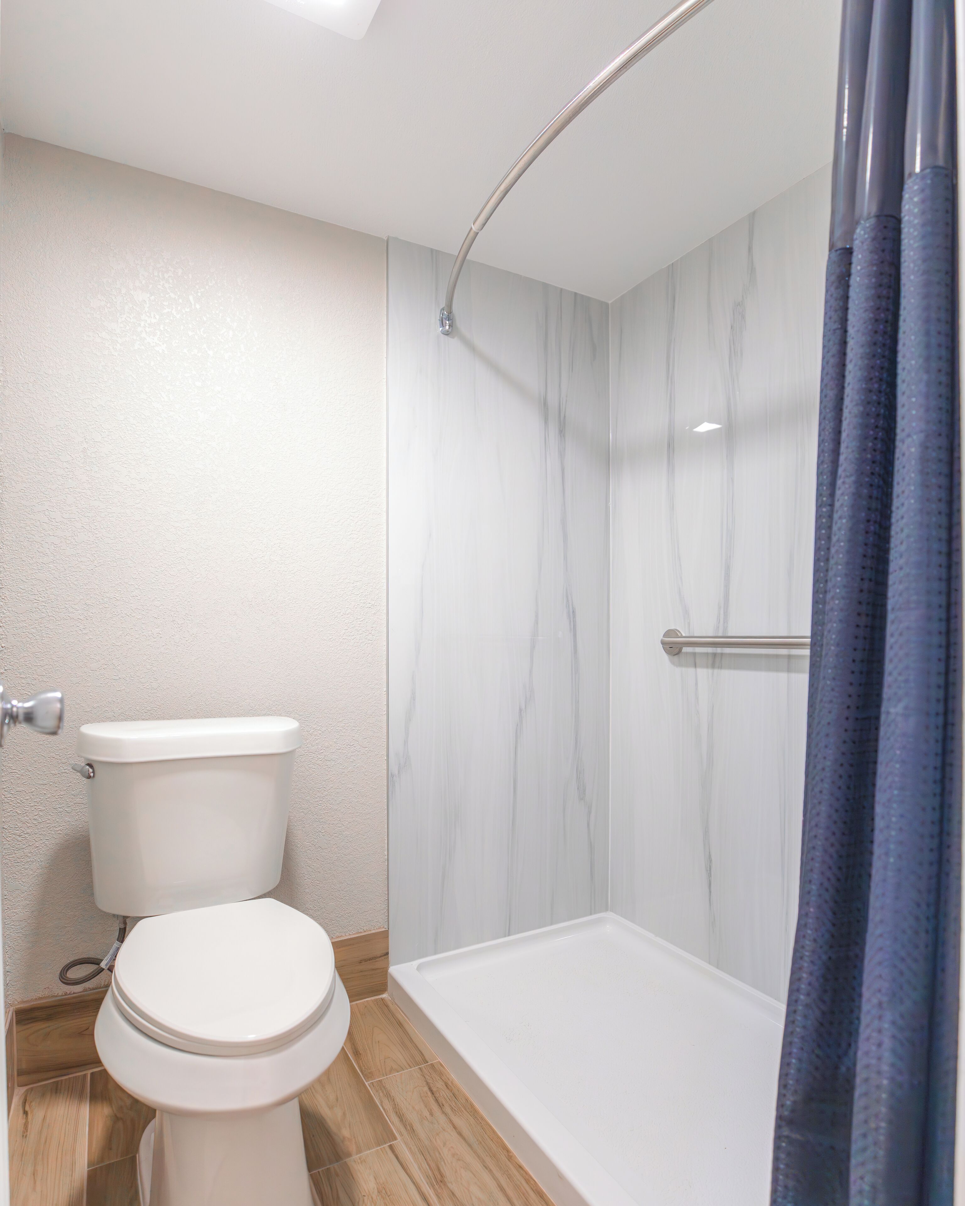 A bathroom with a toilet, a shower with a glass door, and a bathtub.