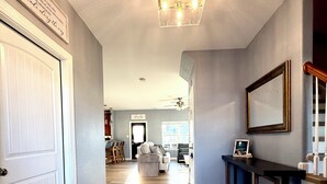 A spacious hallway with a wooden floor, a ceiling fan, and a wall-mounted light fixture.