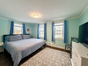 Una camera da letto con un letto, una cassettiera, una sedia e una televisione.