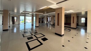 A spacious lobby with a geometric floor pattern, large pillars, and a view of the outdoors. - Hotel Bhagyalaxmi  (Karad)