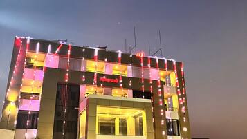 Un edificio con diseño arquitectónico moderno, que destaca por su entrada principal y una serie de luces a lo largo de la fachada.