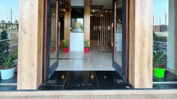 A modern hotel entrance with wooden pillars, a black tiled floor, and potted plants. - Hotel Bhagyalaxmi  (Karad)