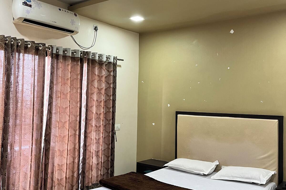 Une chambre d’hôtel équipée d’un lit, d’un ventilateur de plafond, d’un climatiseur et de rideaux.