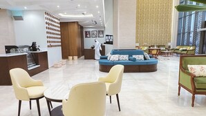 Eine moderne Lobby mit einer Rezeption, einer Sitzecke und einem großen Fenster.