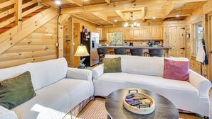 A cozy cabin interior with a wooden staircase, a white sofa, a dining table, and a kitchen area. - 3 Mi to Dtwn Clayton: Cabin w/ Trail Access! (Clayton)