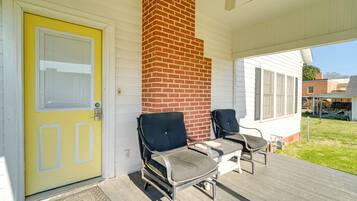 A porch with two chairs and a yellow door.
