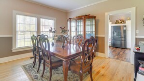 A dining room with a wooden table and chairs, a decorative cabinet, and a kitchen area with a refrigerator. - 10 Mi to Caddo Lake: Charming Cottage in Vivian! (Vivian)