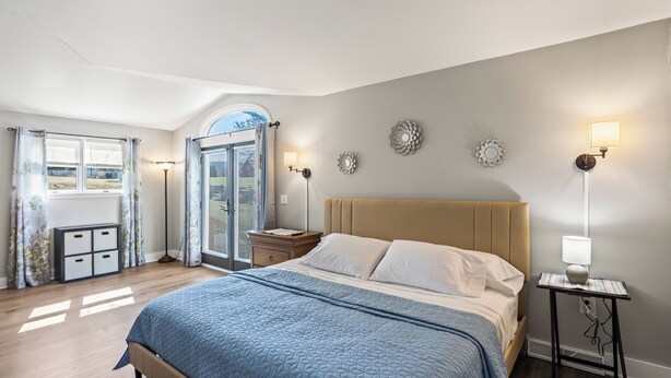 A bedroom with a bed, bedside tables, a nightstand, a dresser, and a window with curtains.