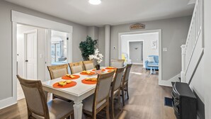 A dining area with a white table, wooden chairs, and orange placemats.