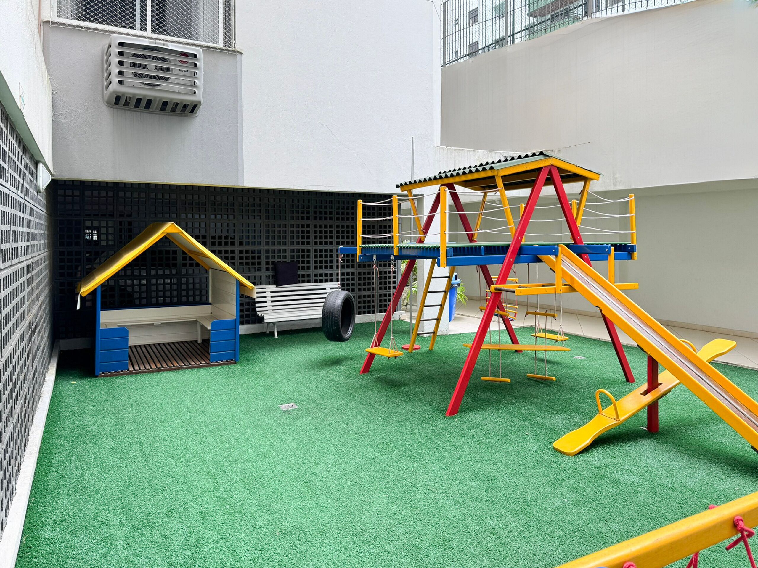 Een kinderspeelplaats met een glijbaan, klimconstructies en een klein huisje.