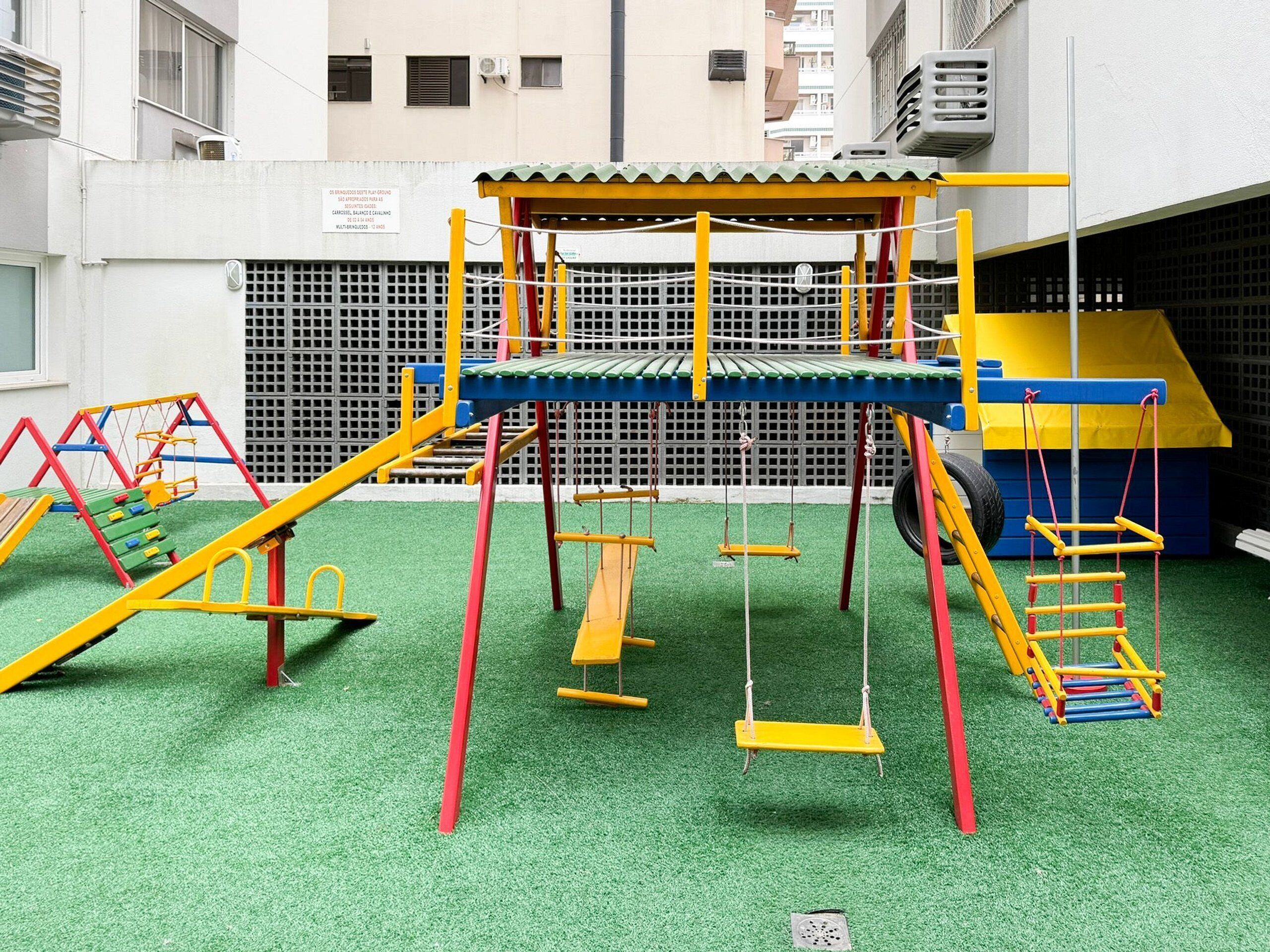 Un parque infantil con una estructura para escalar, columpios y toboganes.