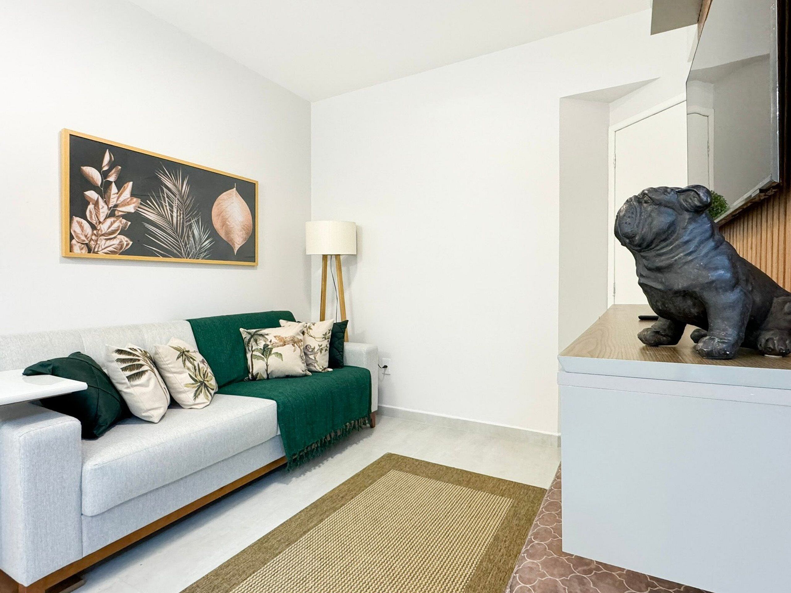 Un salon moderne avec un canapé vert, une lampe et une sculpture décorative.